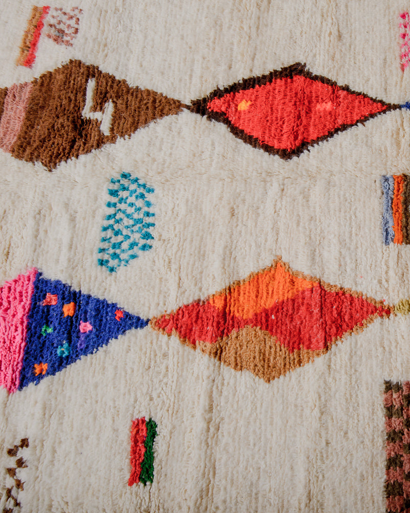 Surface of cream azilal rug with orange, pink, blue and brown diamonds
