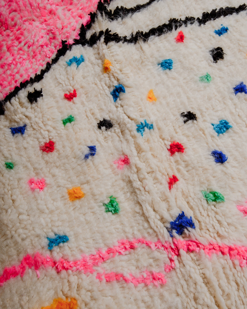 Surface of azilal rug showing soft cream wool and colourful cotton elements. 