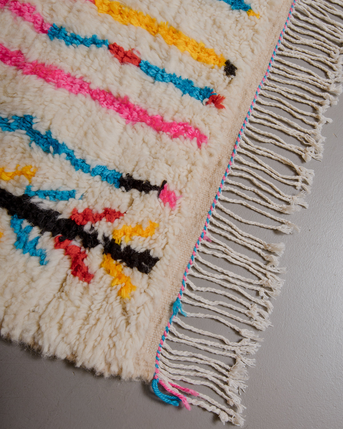 Corner of azilal rug with white cotton tassels.