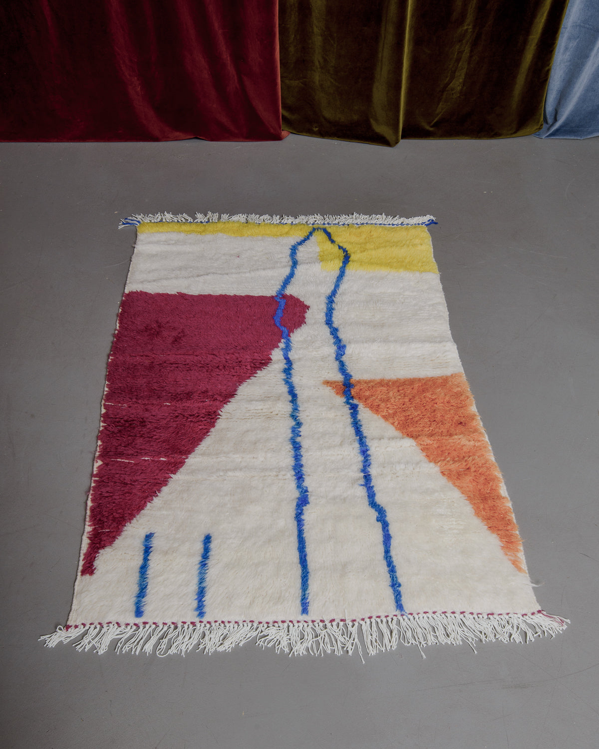 Brightly coloured azilal rug on grey floor.