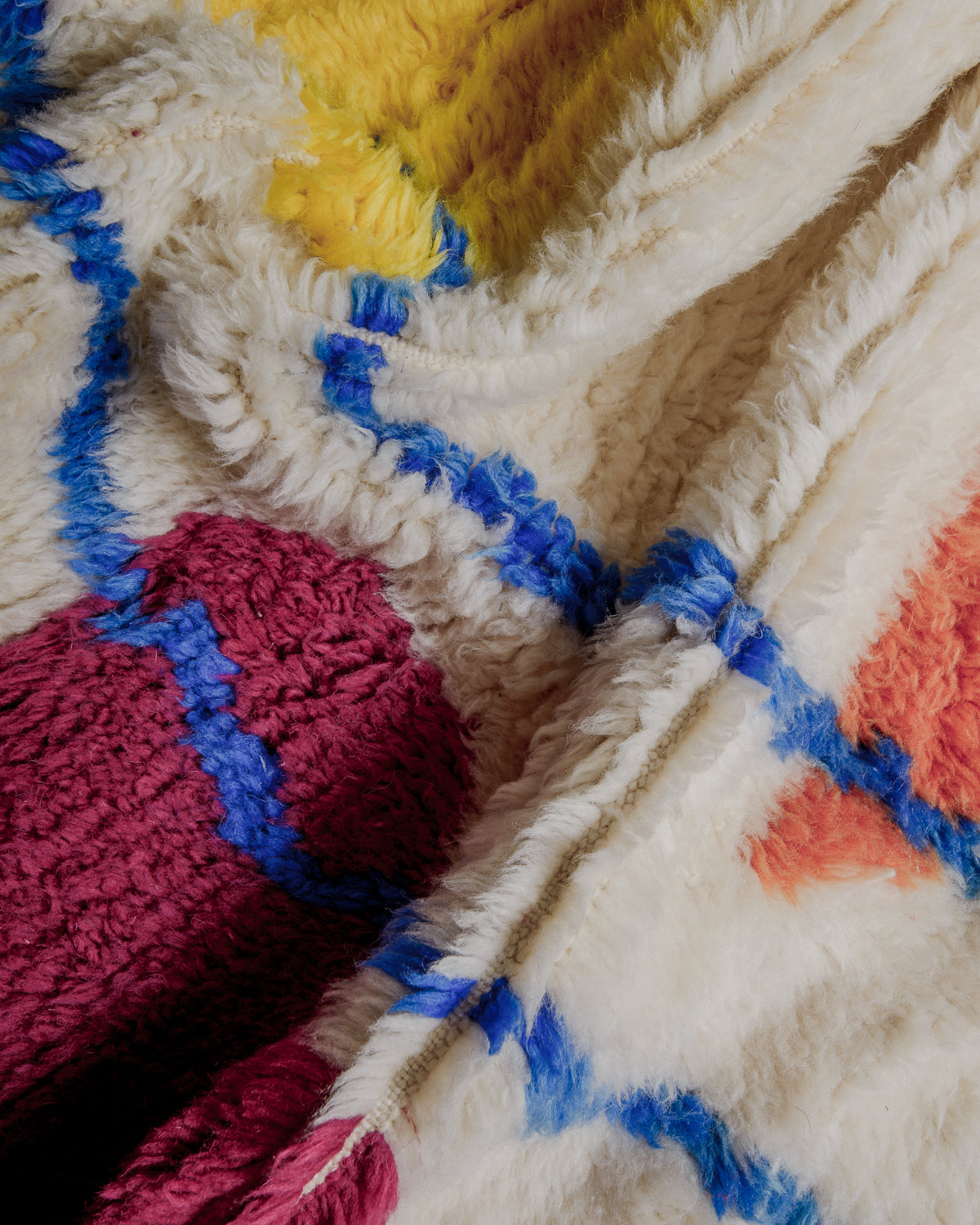 Close up of azilal rug showing fluffy pile made of cream and colourful wool. 