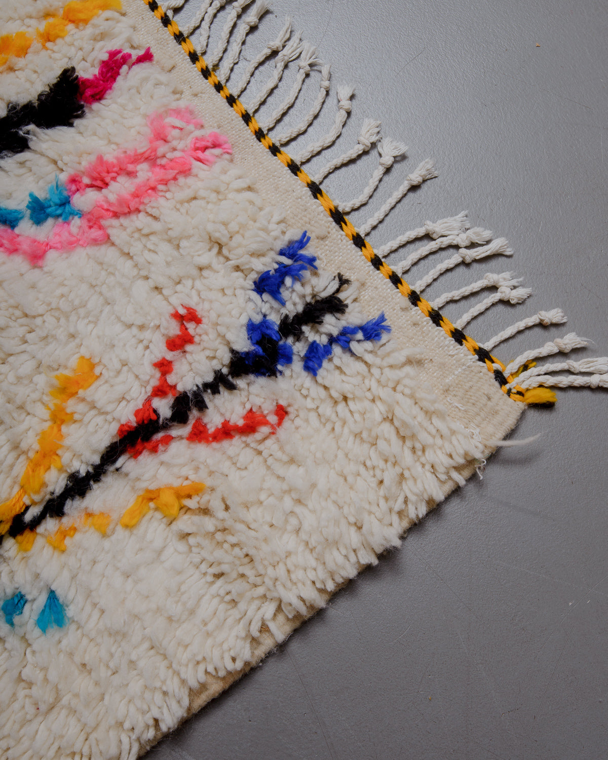 Corner of azilal rug with white cotton tassels.