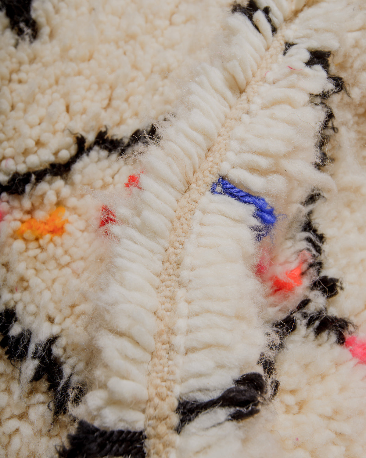 Close-up of a wool rug with colorful accents and thick, cream wool.