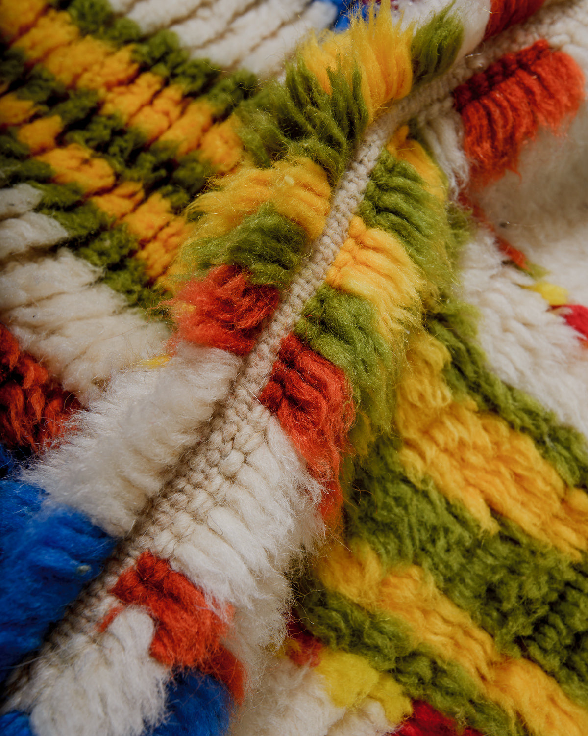 Close-up of a colorful wool rug with red, green, yellow, and blue patterns.