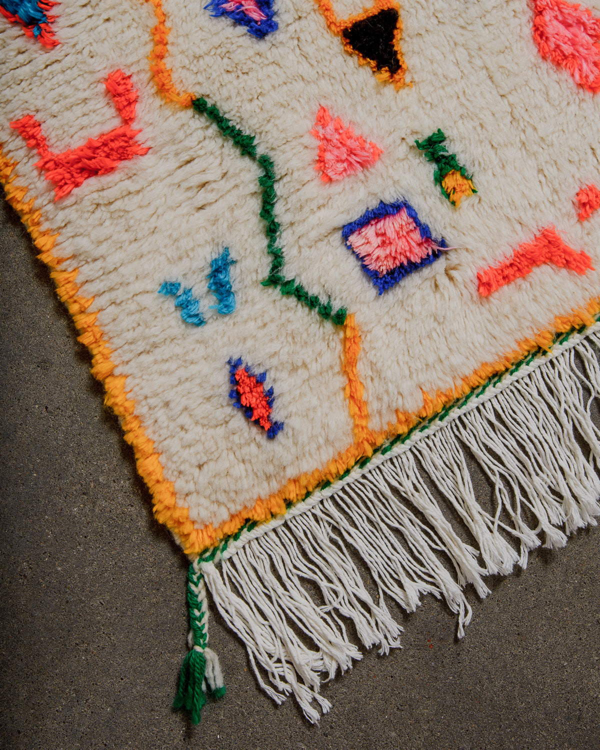 Colorful woven Berberlin Finest rug with white cotton tassels on a neutral background