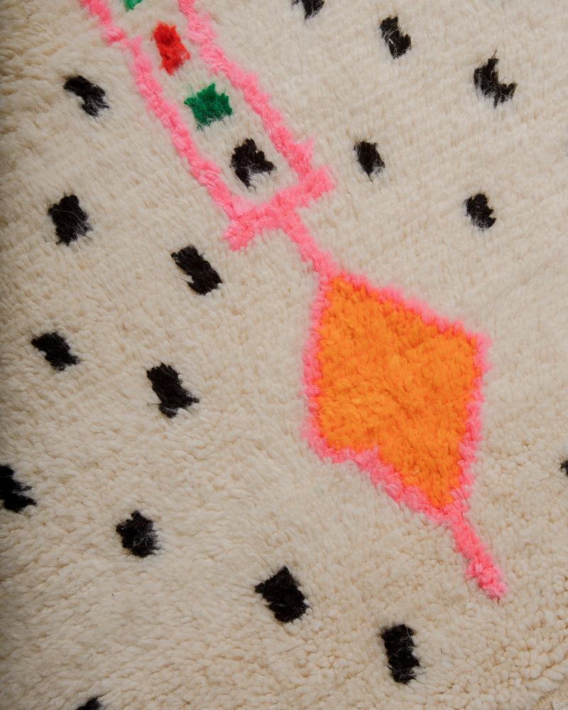 Close up of Azilal rug with black dot pattern and symbol in pink and orange.