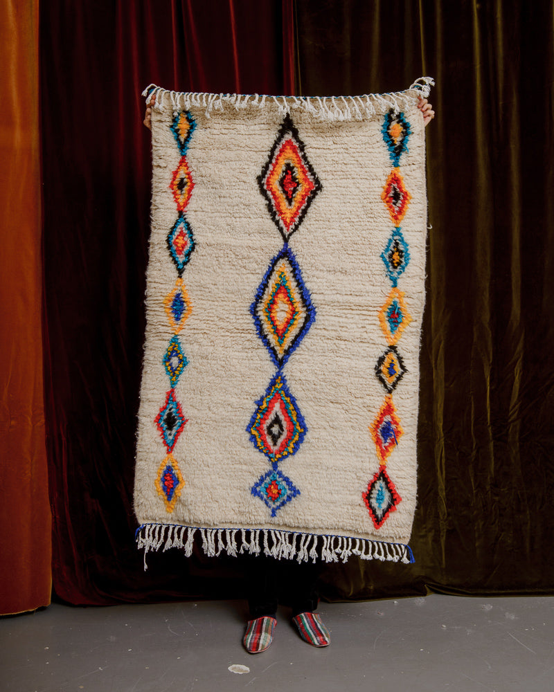 Berberlin Azilal rug in a small size held in front of a velvet wall. 