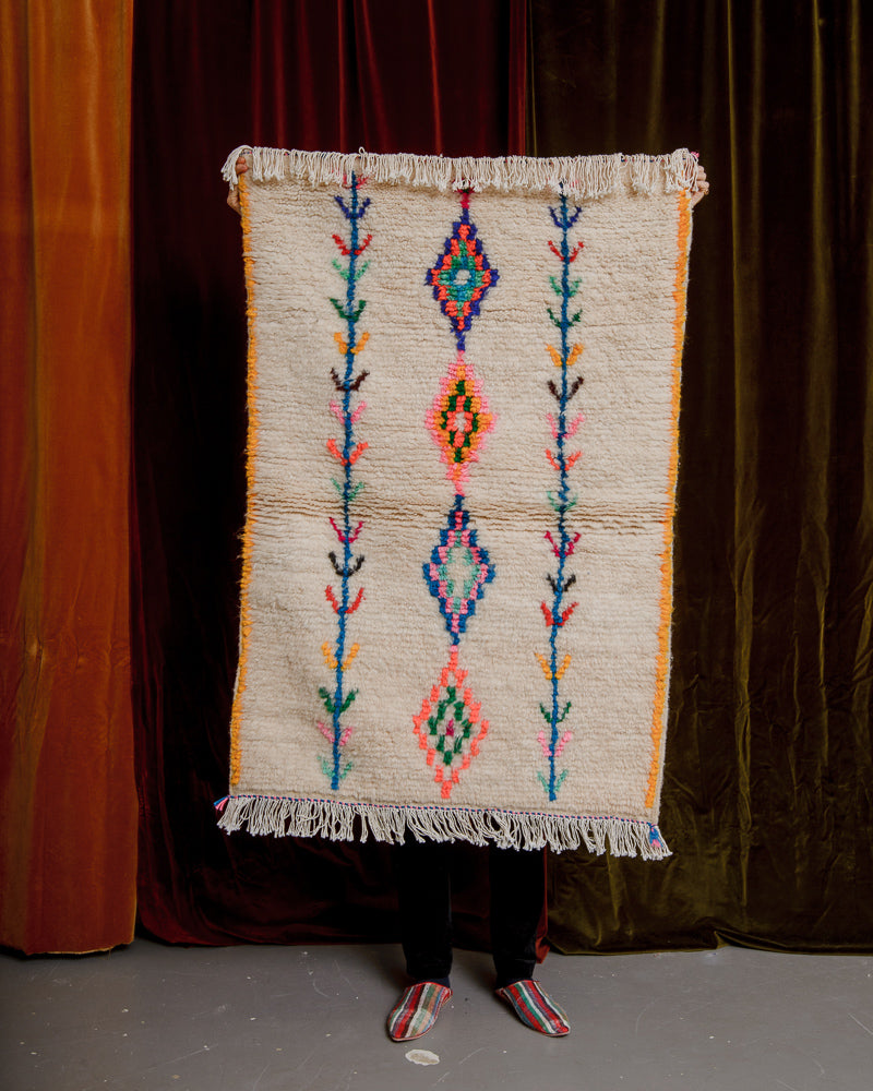 Berberlin Azilal rug in a small size held in front of a velvet wall. 