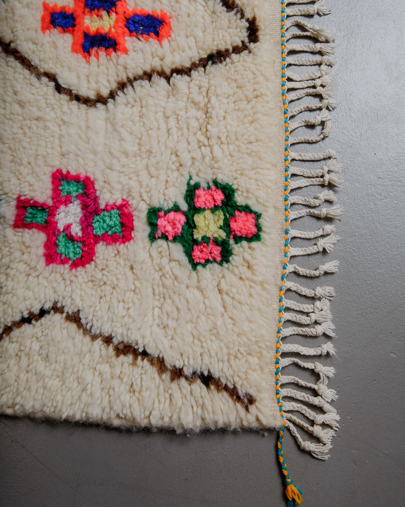 Edge of Azilal rug with cream wool, colourful cotton accents and white cotton tassels.