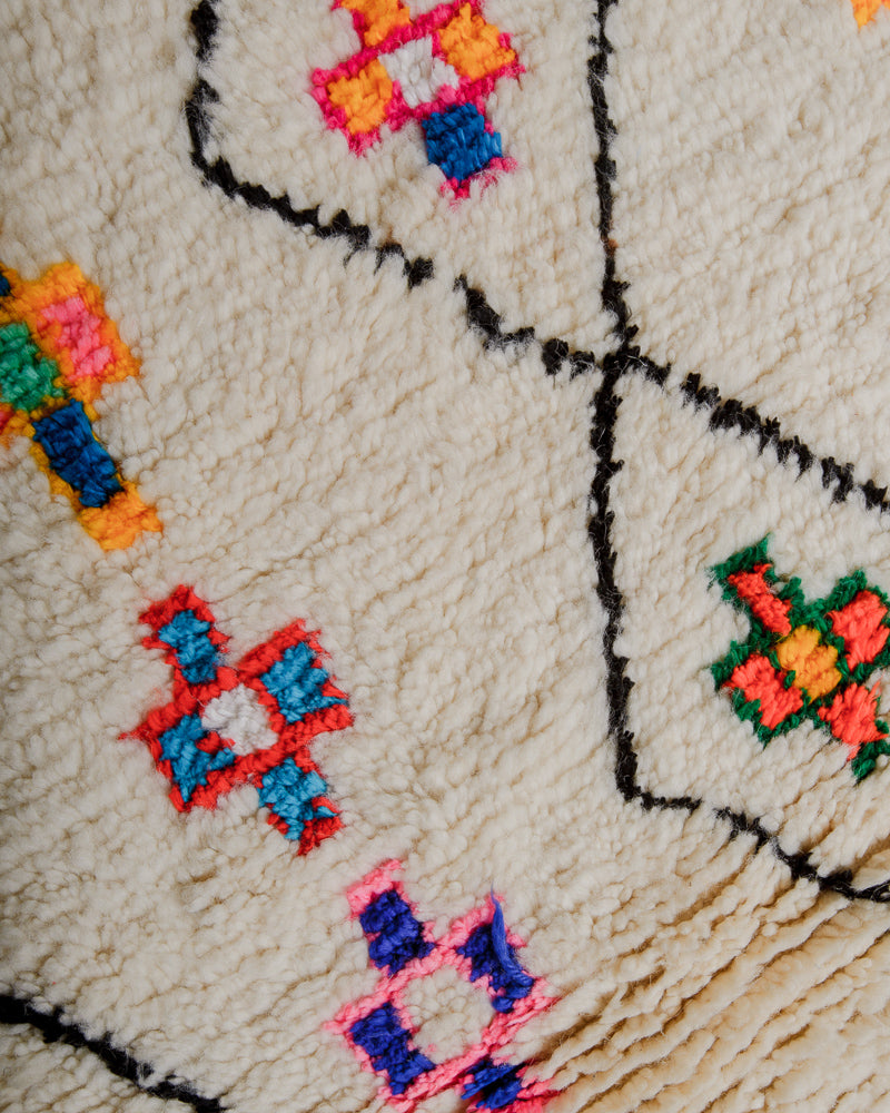 Surface of azilal rug with cream wool and motifs in colourful cotton