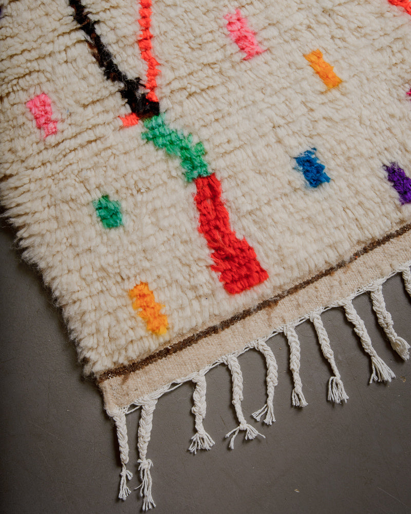 Corner of Berberlin Azilal rug with cream wool and colourful cotton and white cotton tassels.
