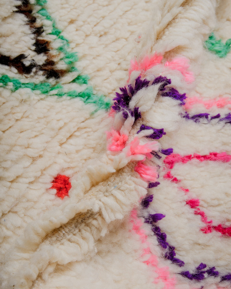 Close up of rug with colourful cotton in turquoise, brown, pink, purple.