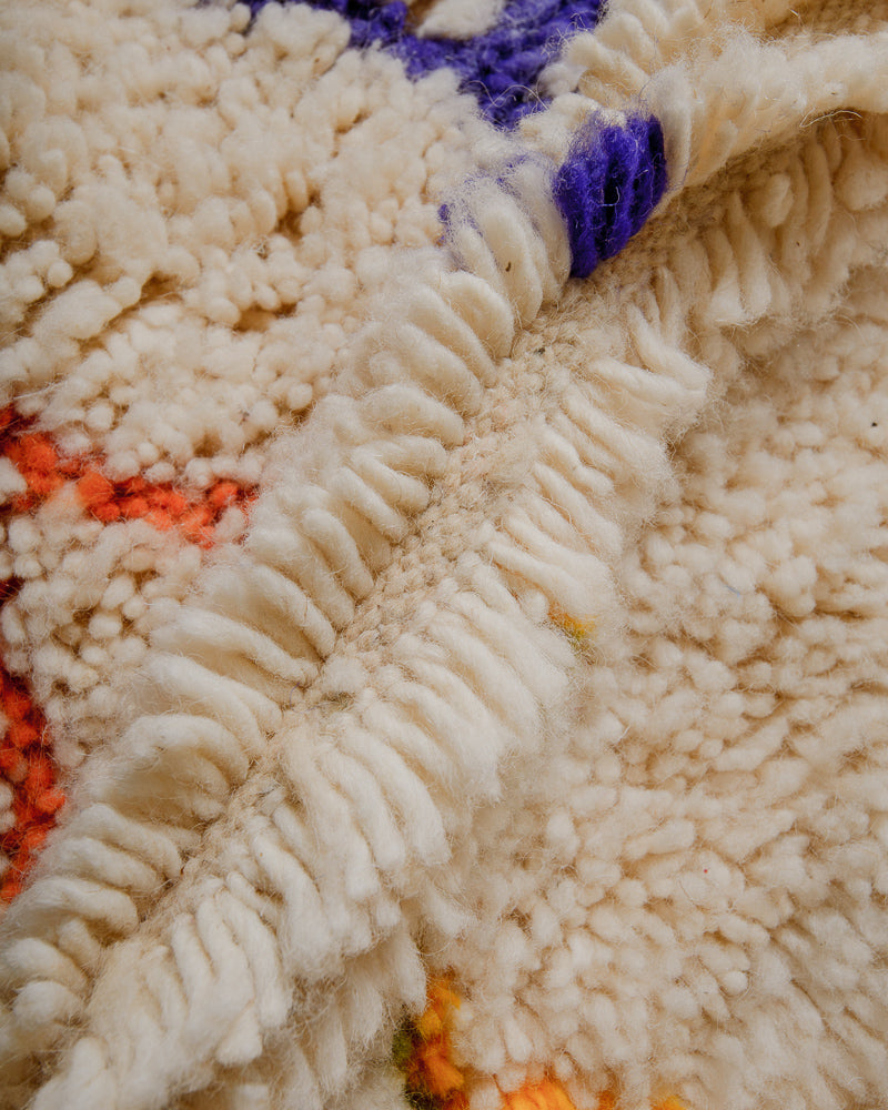 Close up of wool rug with colourful accents in purple, orange and yellow.