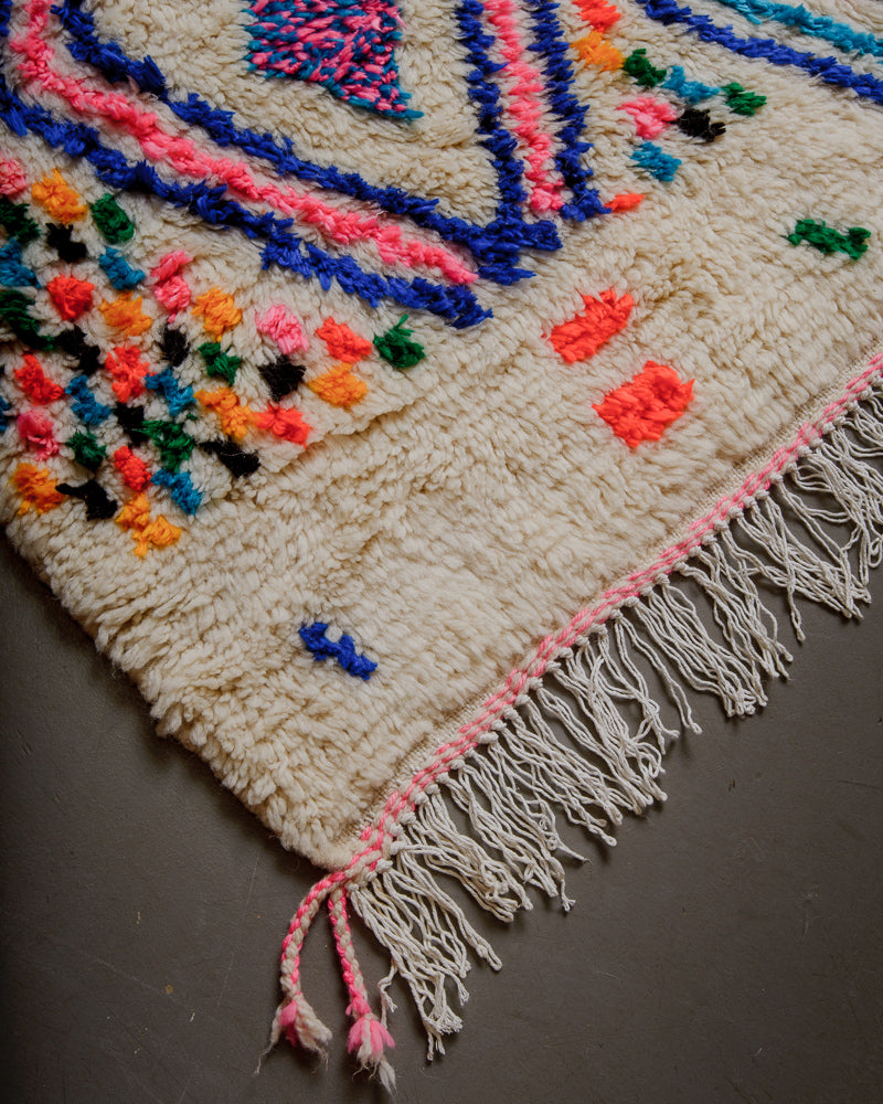 Corner of Berberlin Azilal rug with cream wool and colourful cotton and white cotton fringe.