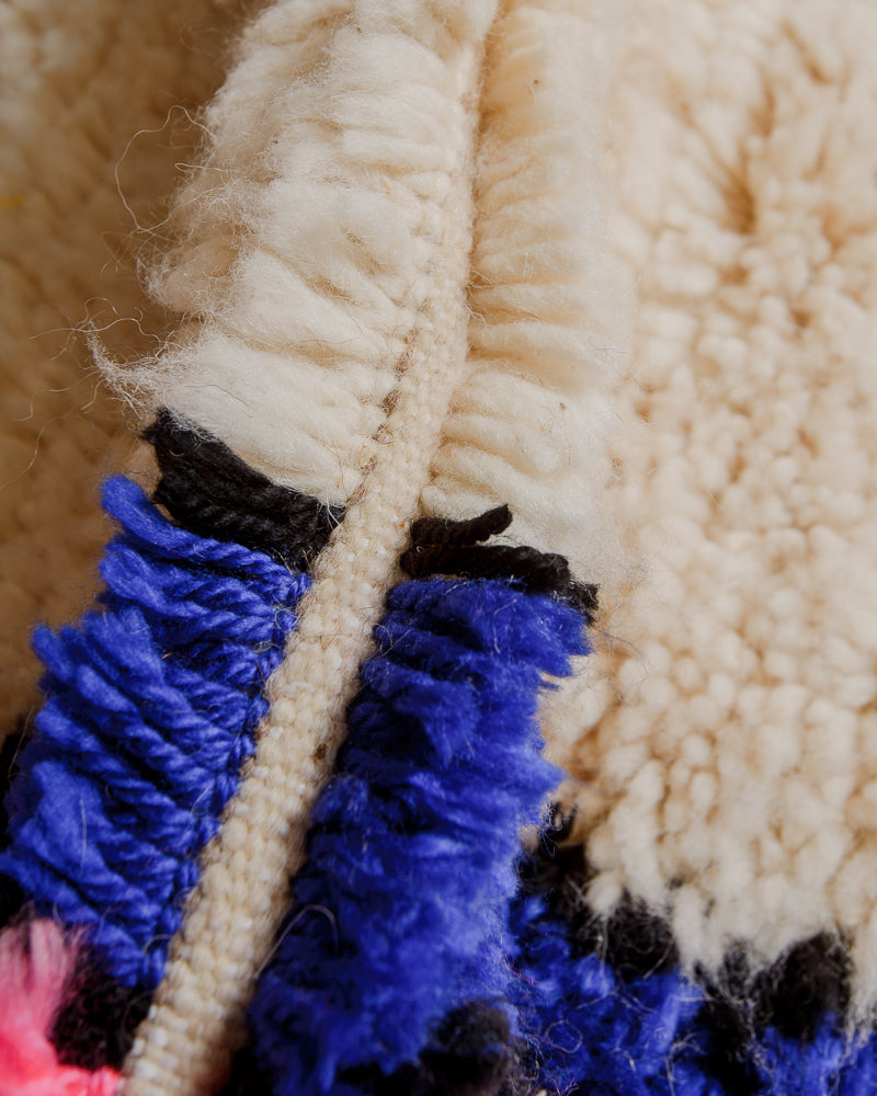 Close up of rug with colourful yarn in blue, pink and black.