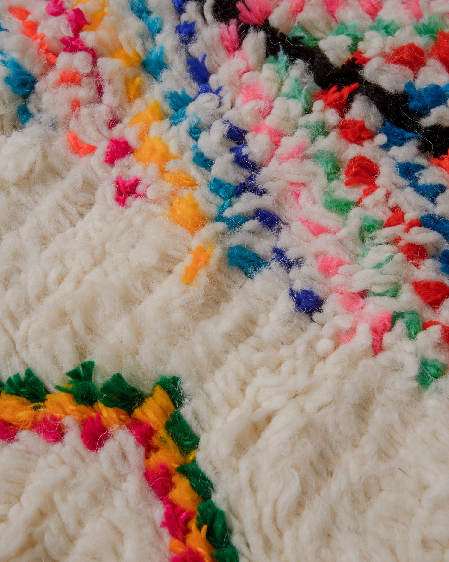Detail of surface of cream azilal rug with confetti colours.