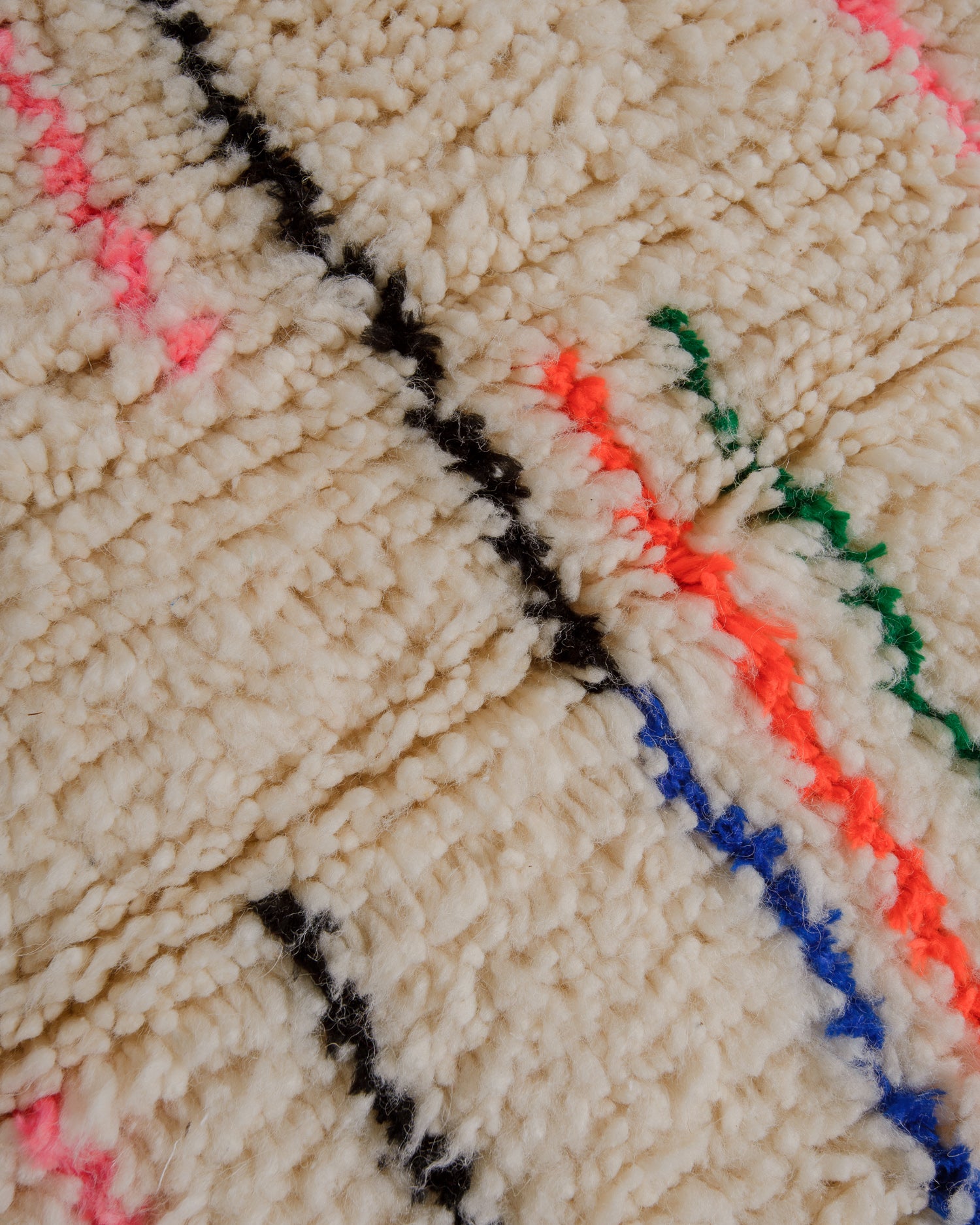 Surface of fluffy azilal rug with black, orange, green and blue lines.