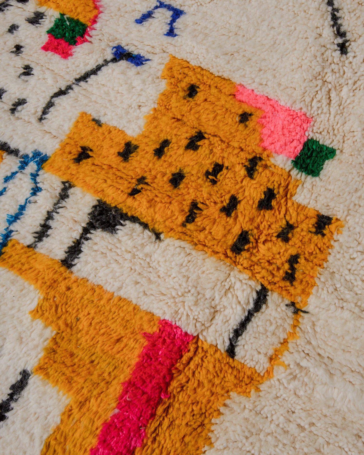 Detail of cream wool azilal rug with a design in mustard with black dots. 