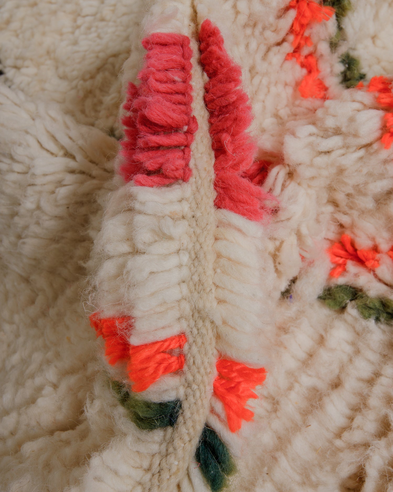 Close up of fluffy wool azilal rug with colourful details in khaki, orange and pink. 