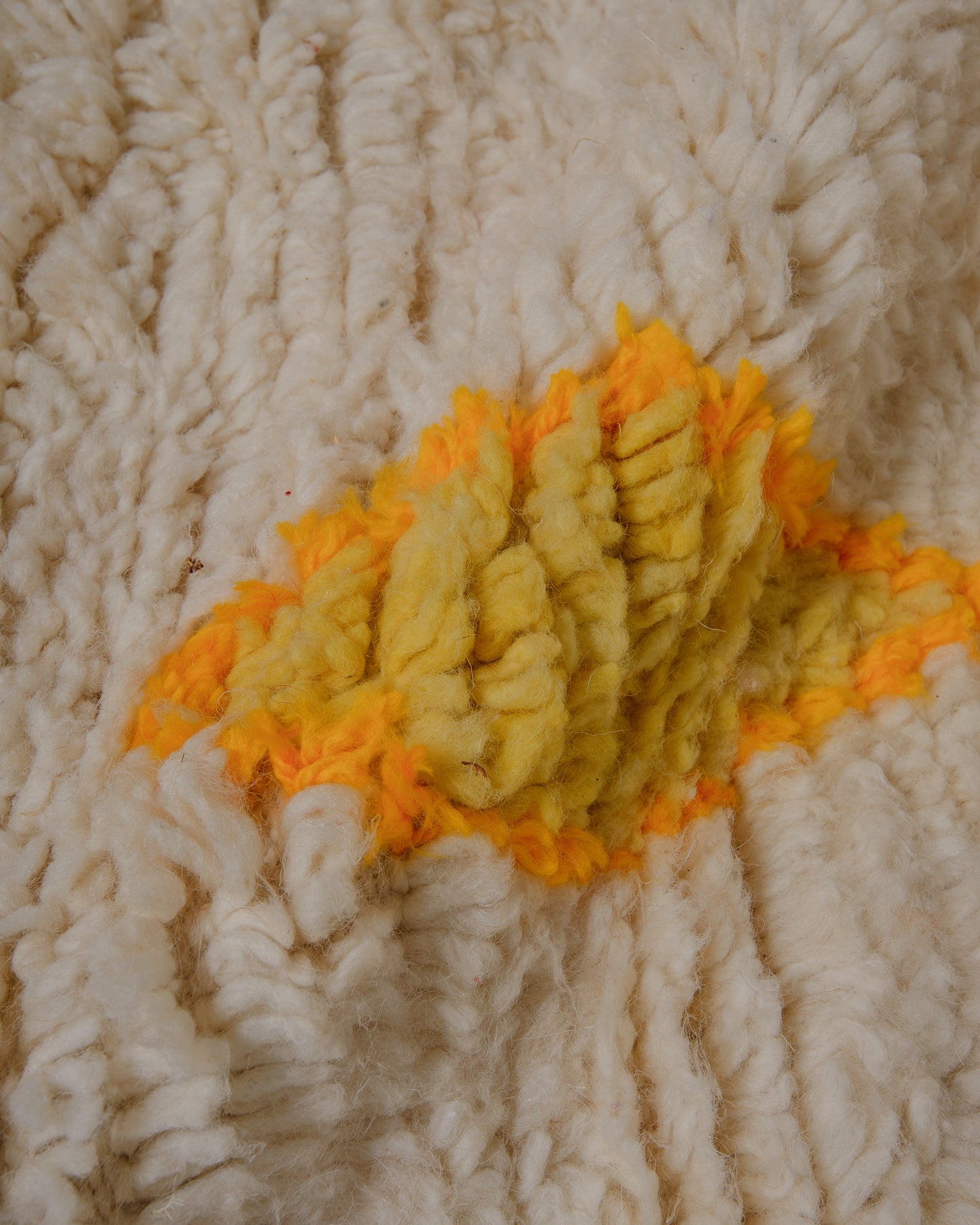 Close up of surface of fluffy wool azilal rug featuring a lemon yellow diamond motif bordered with sunflower yellow.
