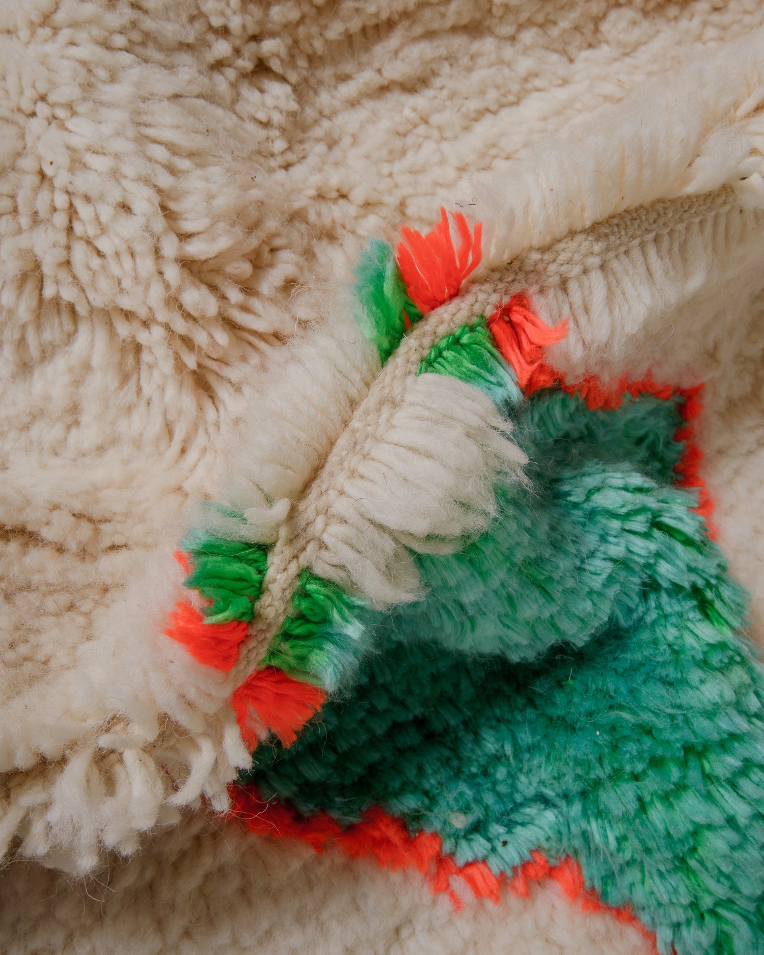 Close up of cream wool azilal rug with brightly coloured design elements.