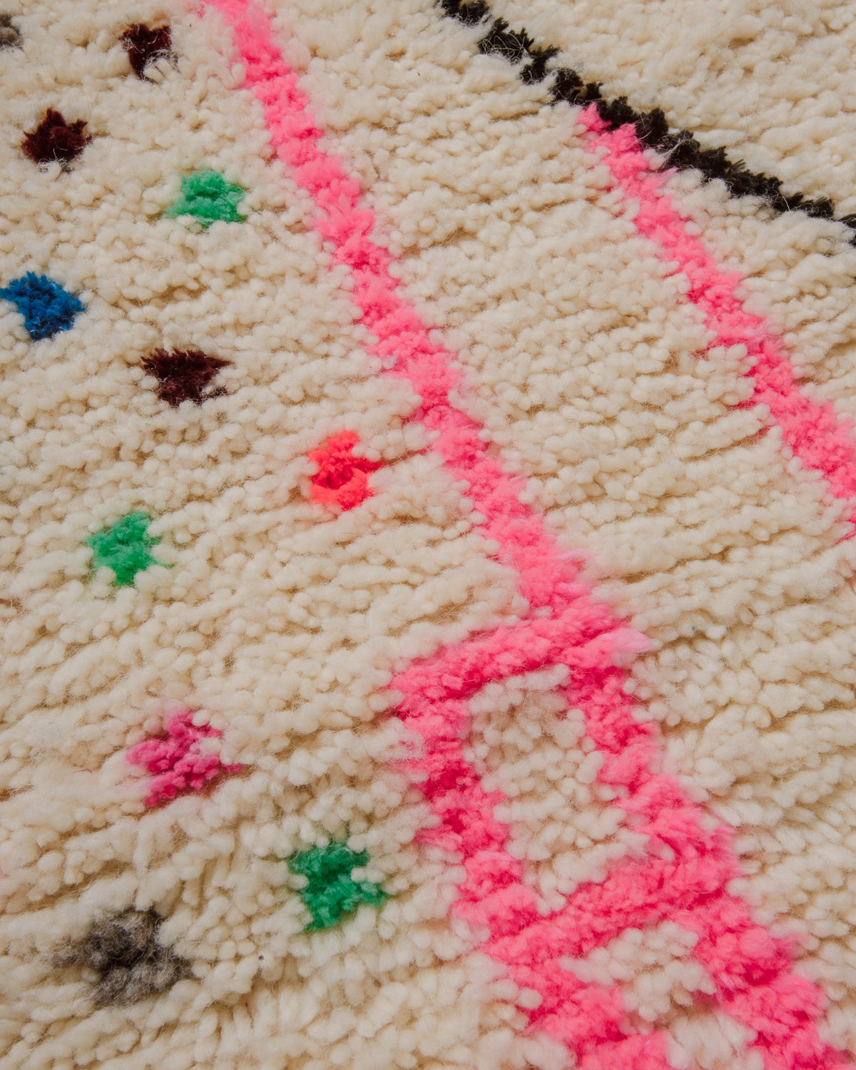 Close-up of a textured Azilal surface with pink and green accents.