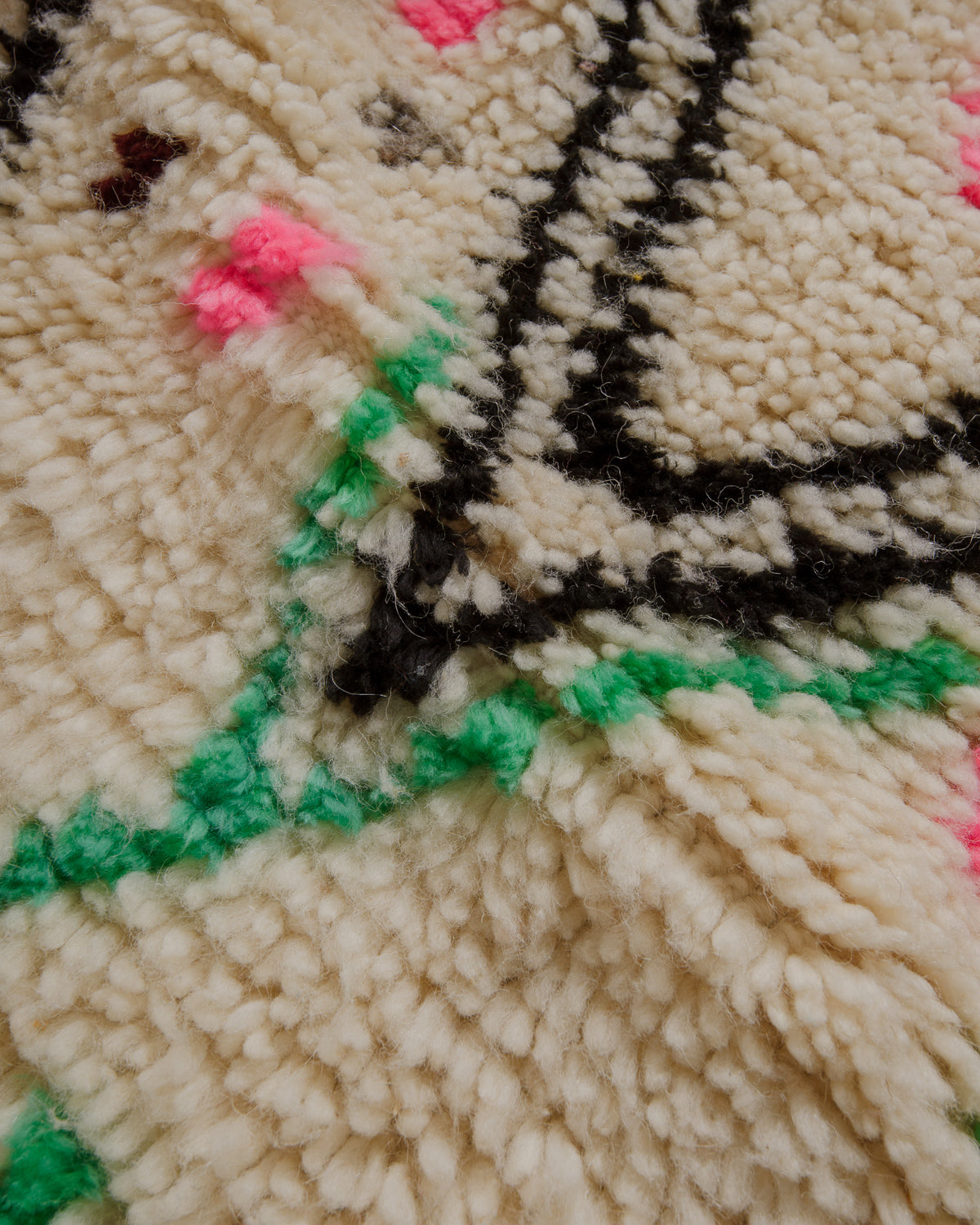 Fluffy surface of azilal rug with black, green and pink accents. 