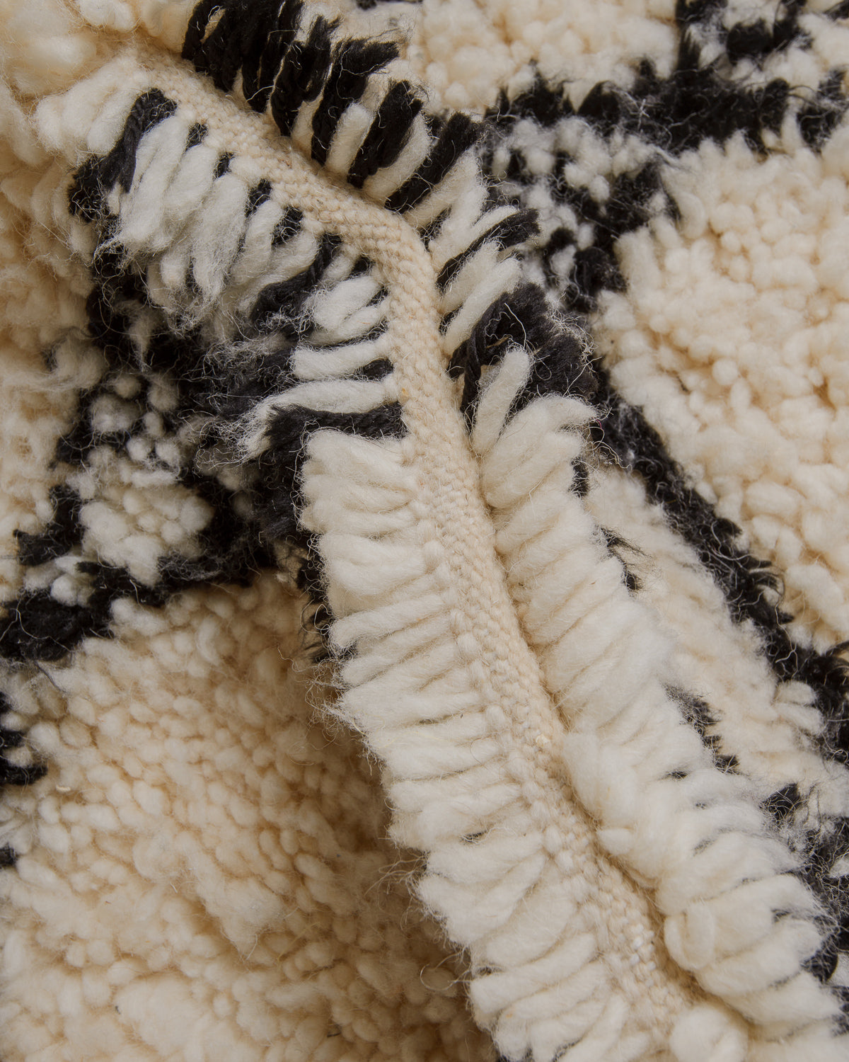Close-up of textured rug with black and cream pattern.