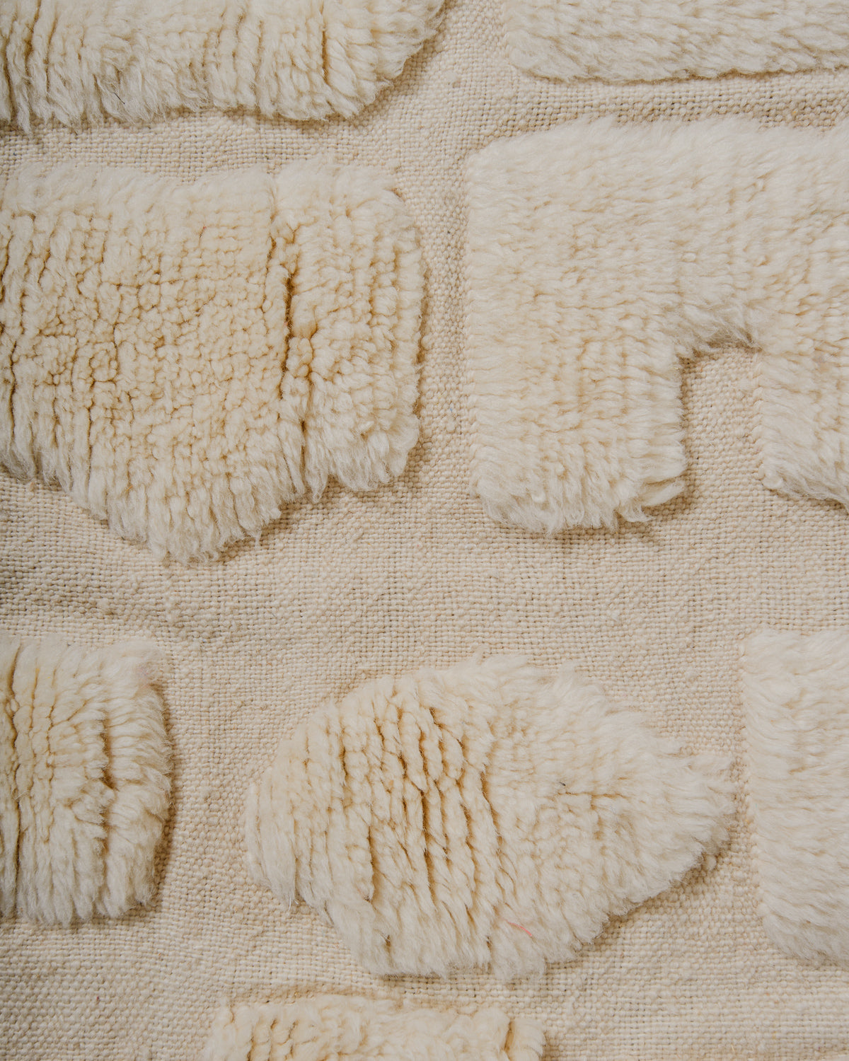 Close-up of textured cream wool rug with raised patterns