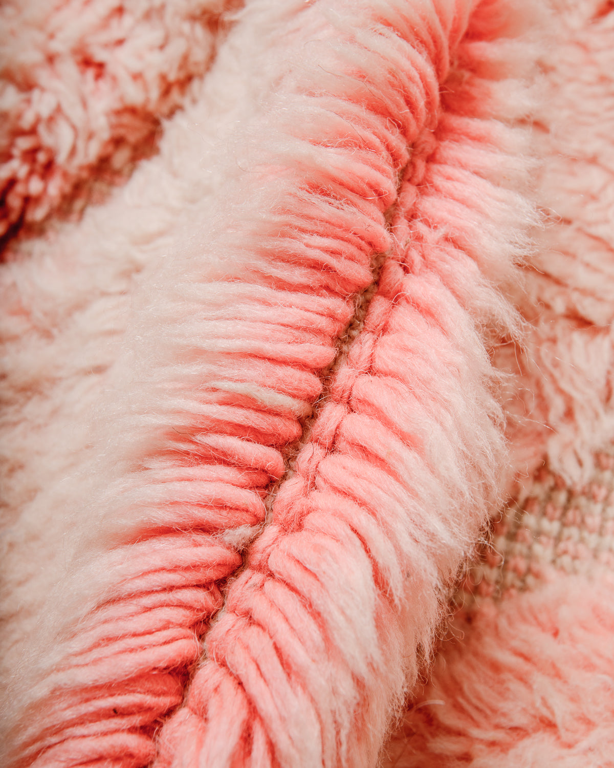 Detail of wool of Berberlin M'rirt rug showing thick wool pile, dense knots and the gradient of the colour from darker pink to lighter pink at the tips. 