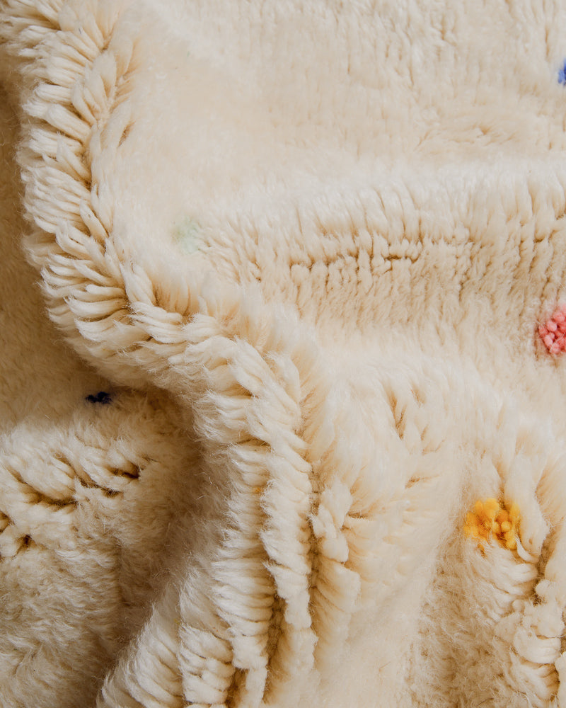 Close-up of cream wool rug with colourful dots.