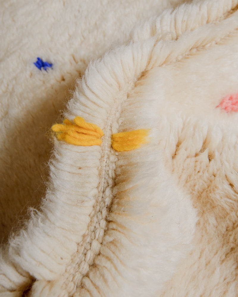 Close-up of cream wool rug with colourful dots.
