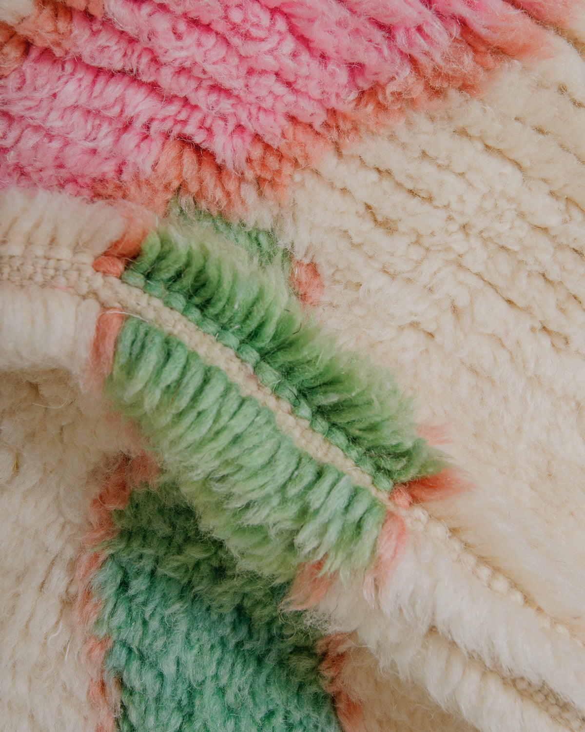 Close-up of a fluffy wool rug with pink and green colours.