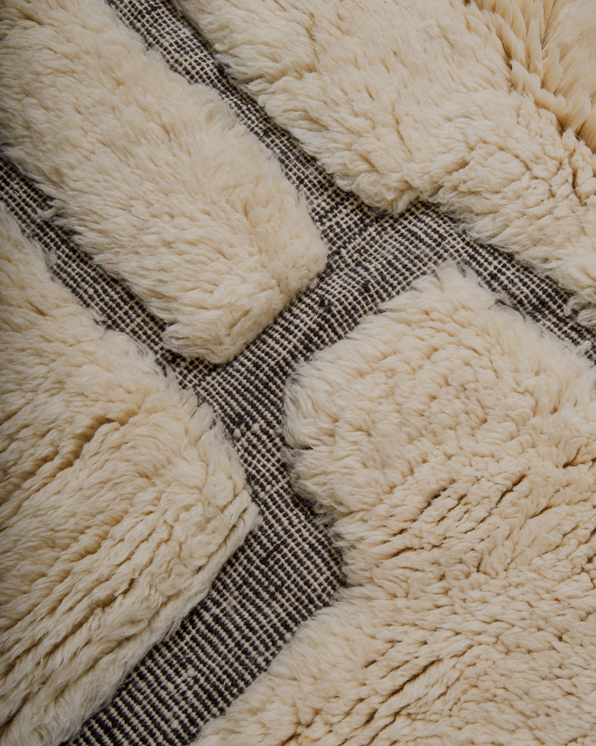 Close up of textured surface of wool rug with knotted and woven areas. 