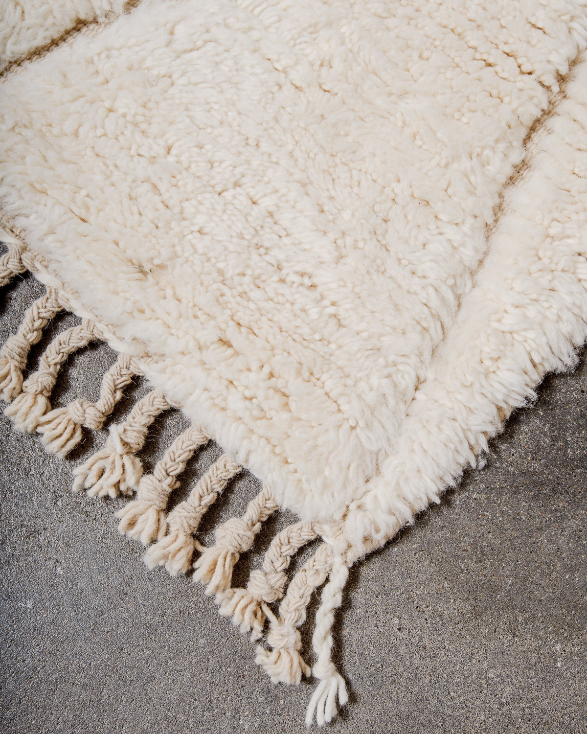 Corner of cream Berber rug with natural wool tassels.