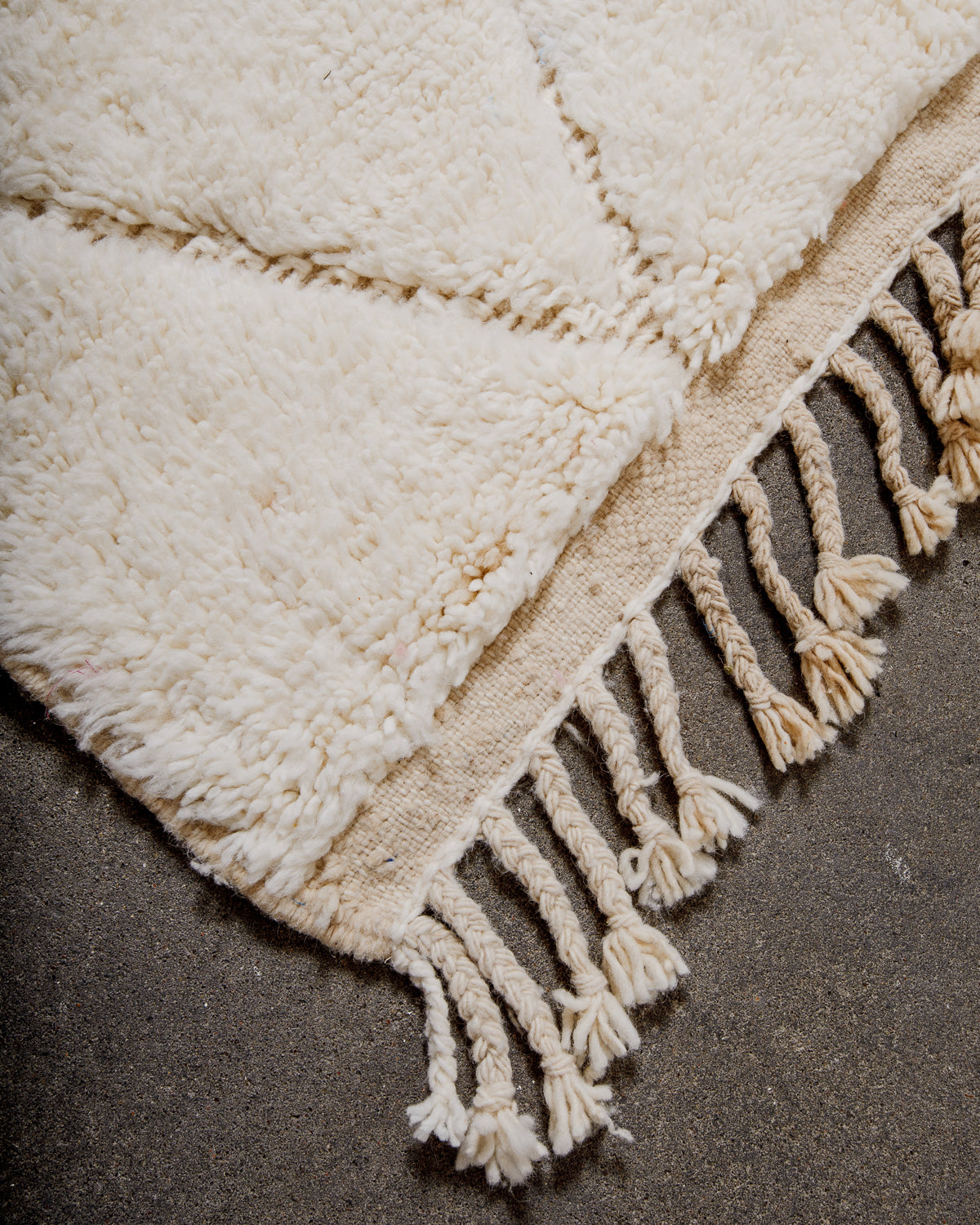 Corner of cream Berber rug with natural wool tassels.