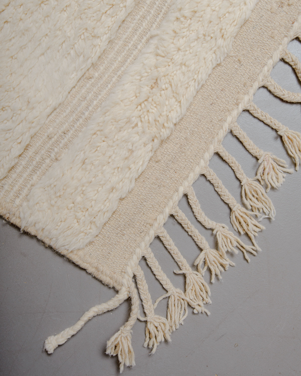 Corner of wool rug with natural tassels.