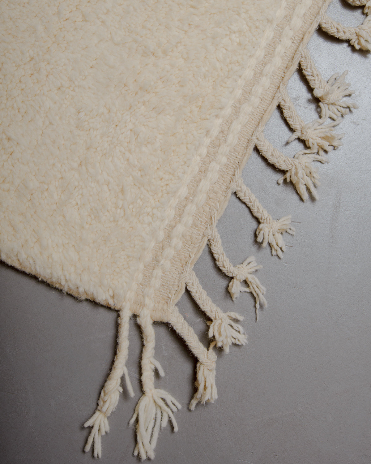 Corner of wool rug with natural tassels.