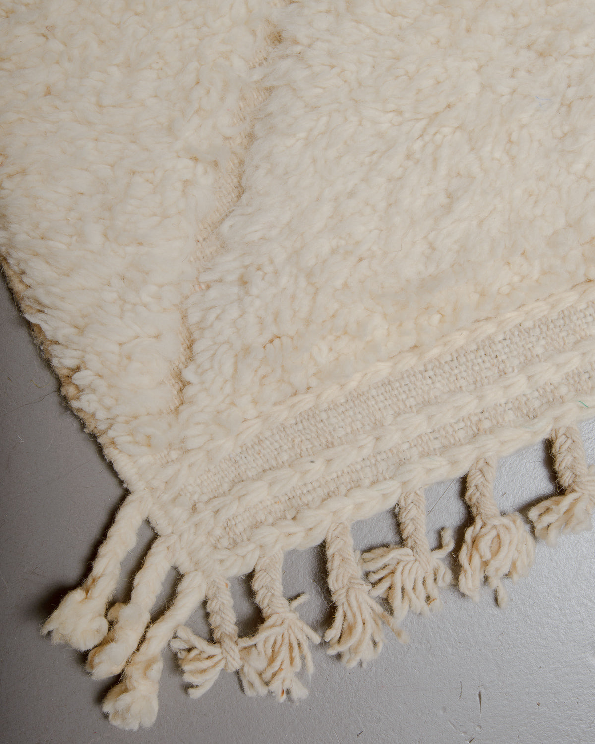 Corner of wool rug with natural tassels.