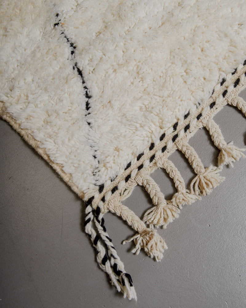 Corner of wool rug with natural tassels.