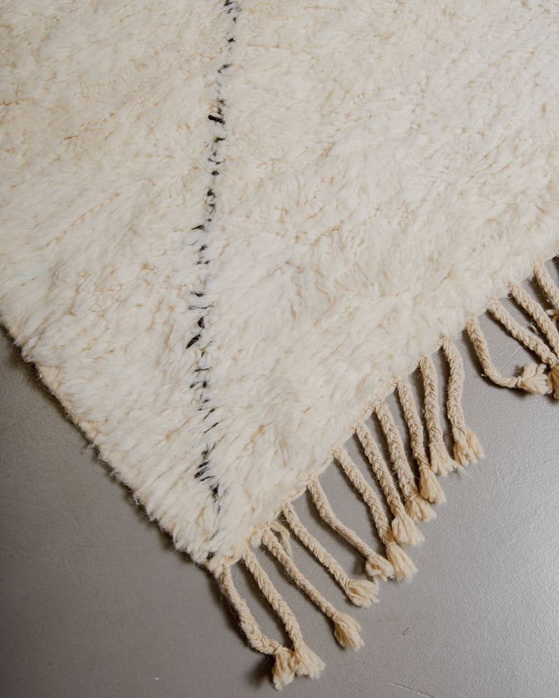 Corner of wool rug with natural tassels.