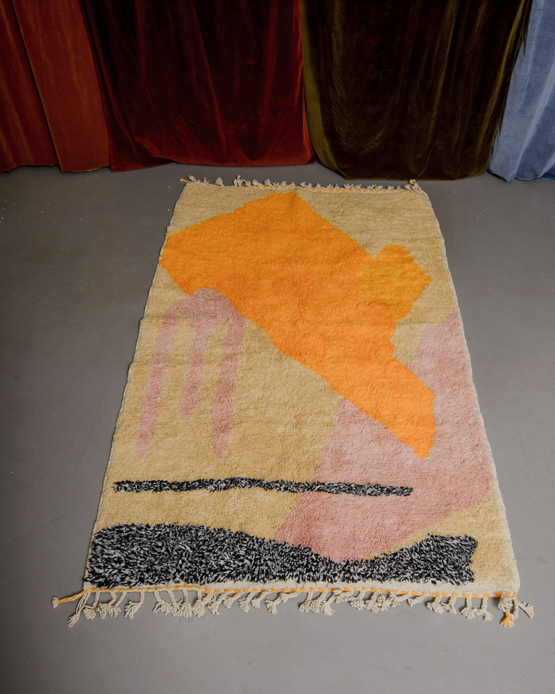 Colourful Berberlin rug in orange, rose and faded yellow on a grey floor. 
