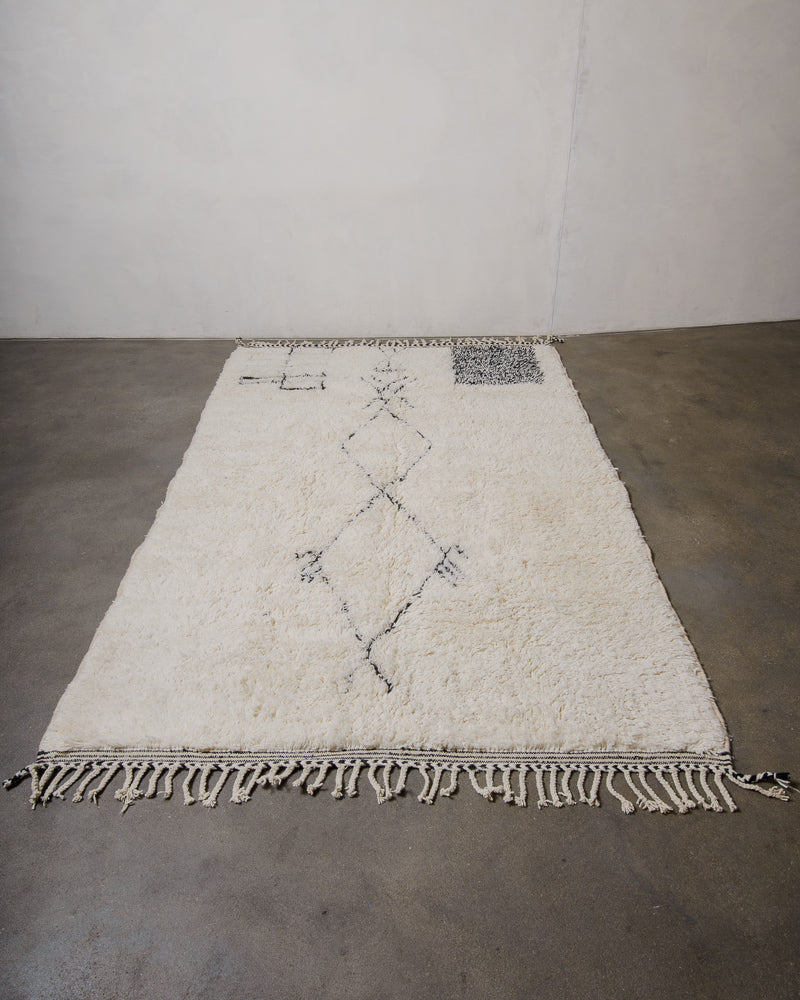 Beniourain rug with geometric patterns and traditional symbols on a gray floor