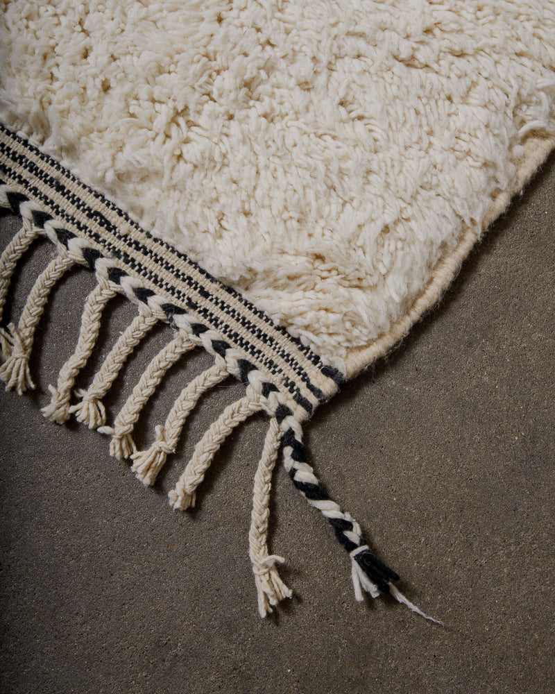 Black and white rug with tassels on a dark surface