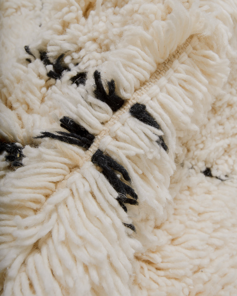 Close-up of wool rug with black and white wool, showing uneven pile giving the rug a shaggy texture.