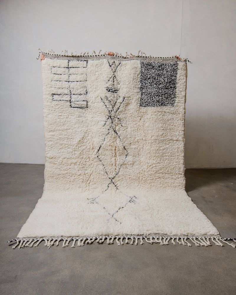 Beniourain rug with geometric patterns and traditional symbols on a plain background