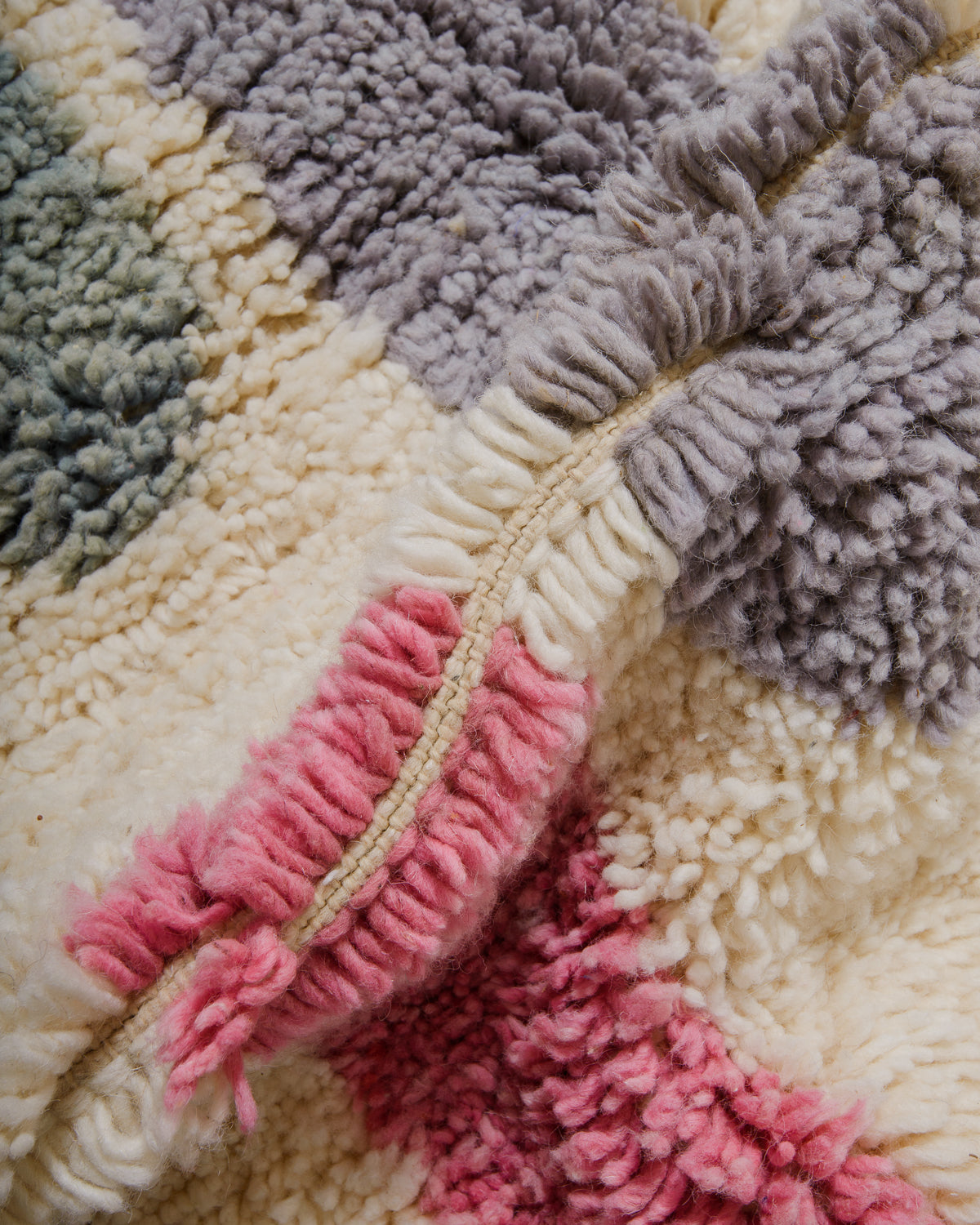 Close-up of a textured wool with pink, sage, and lavender colours.