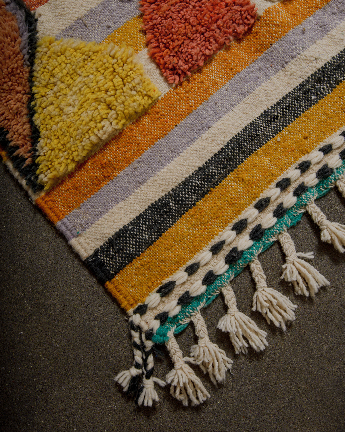 Multicolored textured rug with tassels on a dark surface