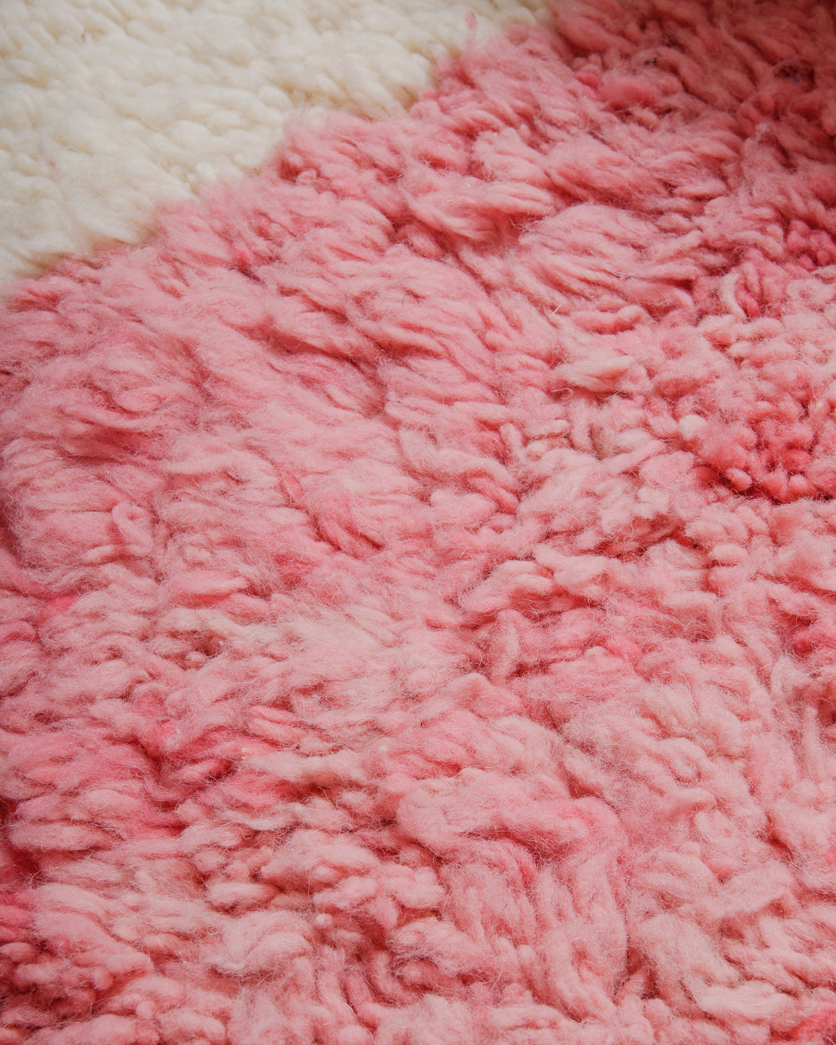 Close-up of a fluffy pink and cream rug surface.