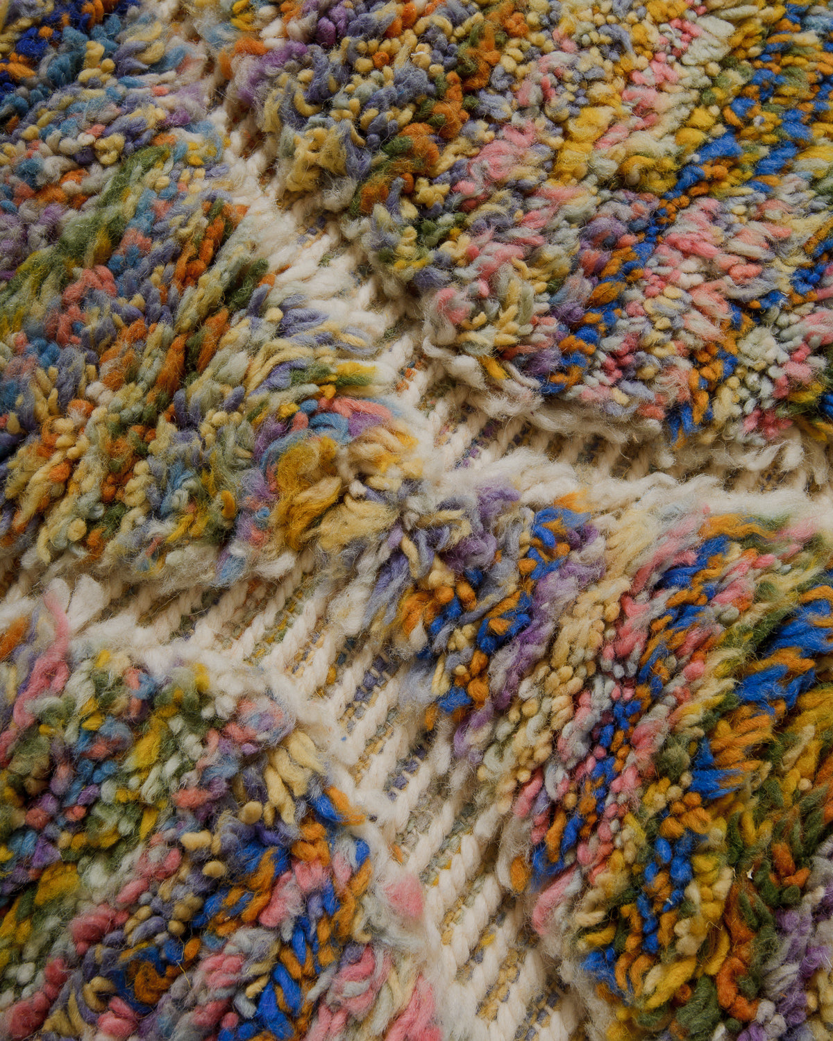 Close-up of a textured, multicolored wool rug with intricate pattern.